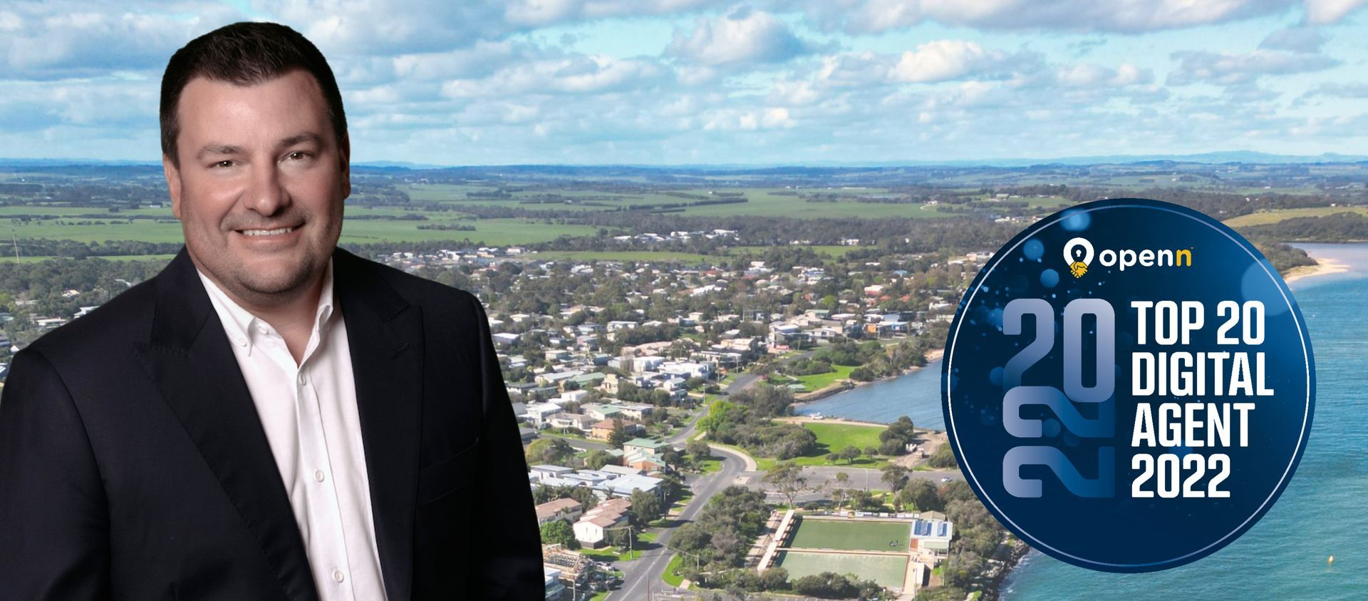 A man in a suit is standing in front of an aerial view of a city.