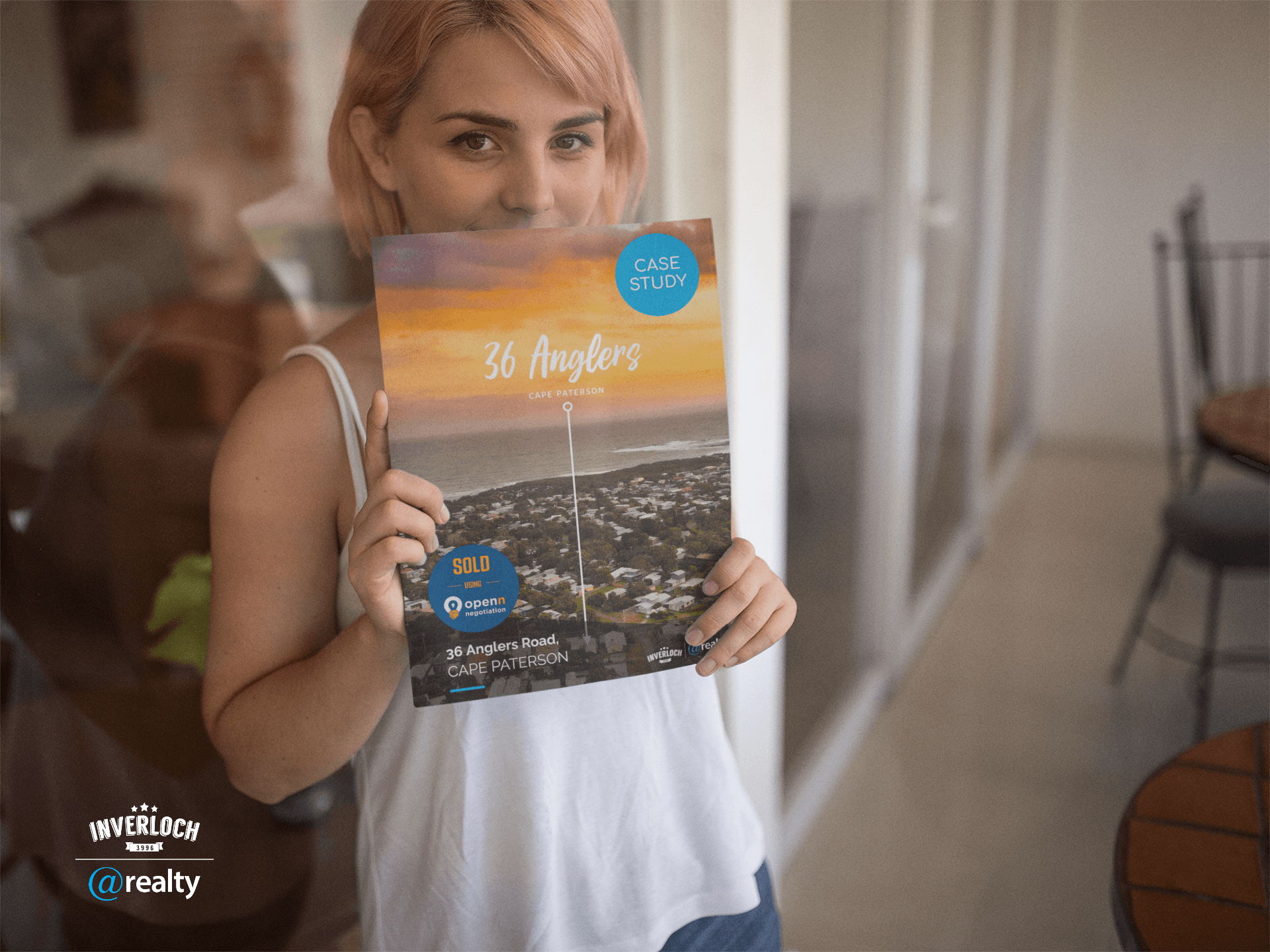 A woman is holding a book in front of her face.