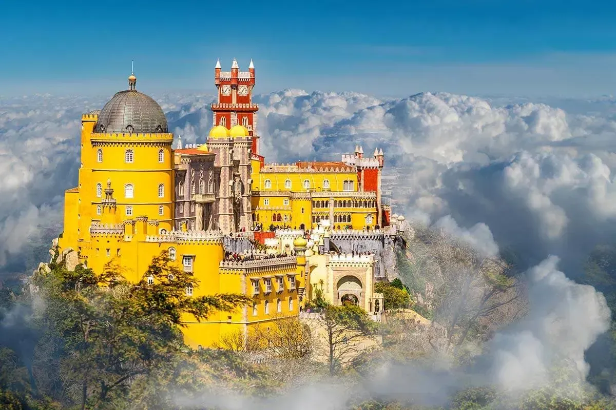 A castle sitting on top of a mountain surrounded by clouds.