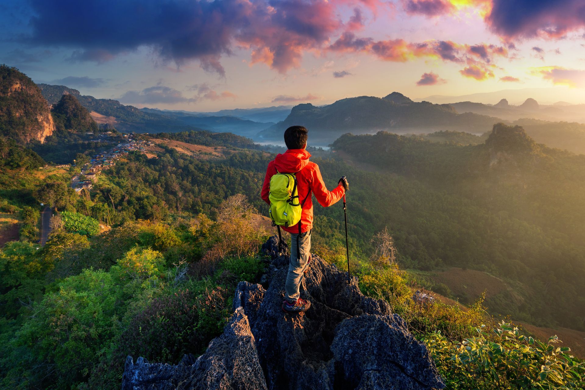 A man with a backpack is standing on top of a mountain.