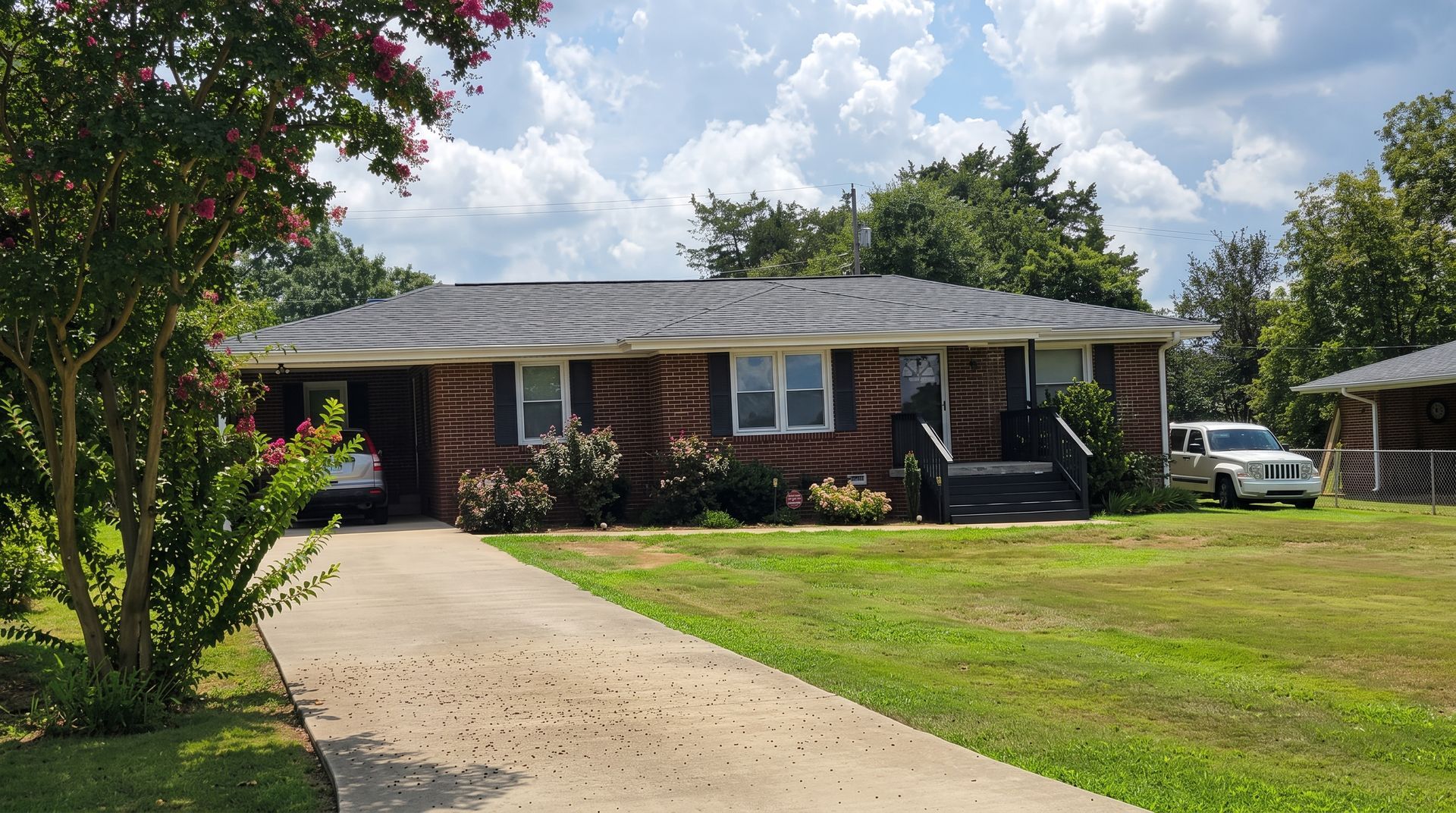 Suburban house with beige siding, blue shutters, a two-car garage, and a landscaped front yard