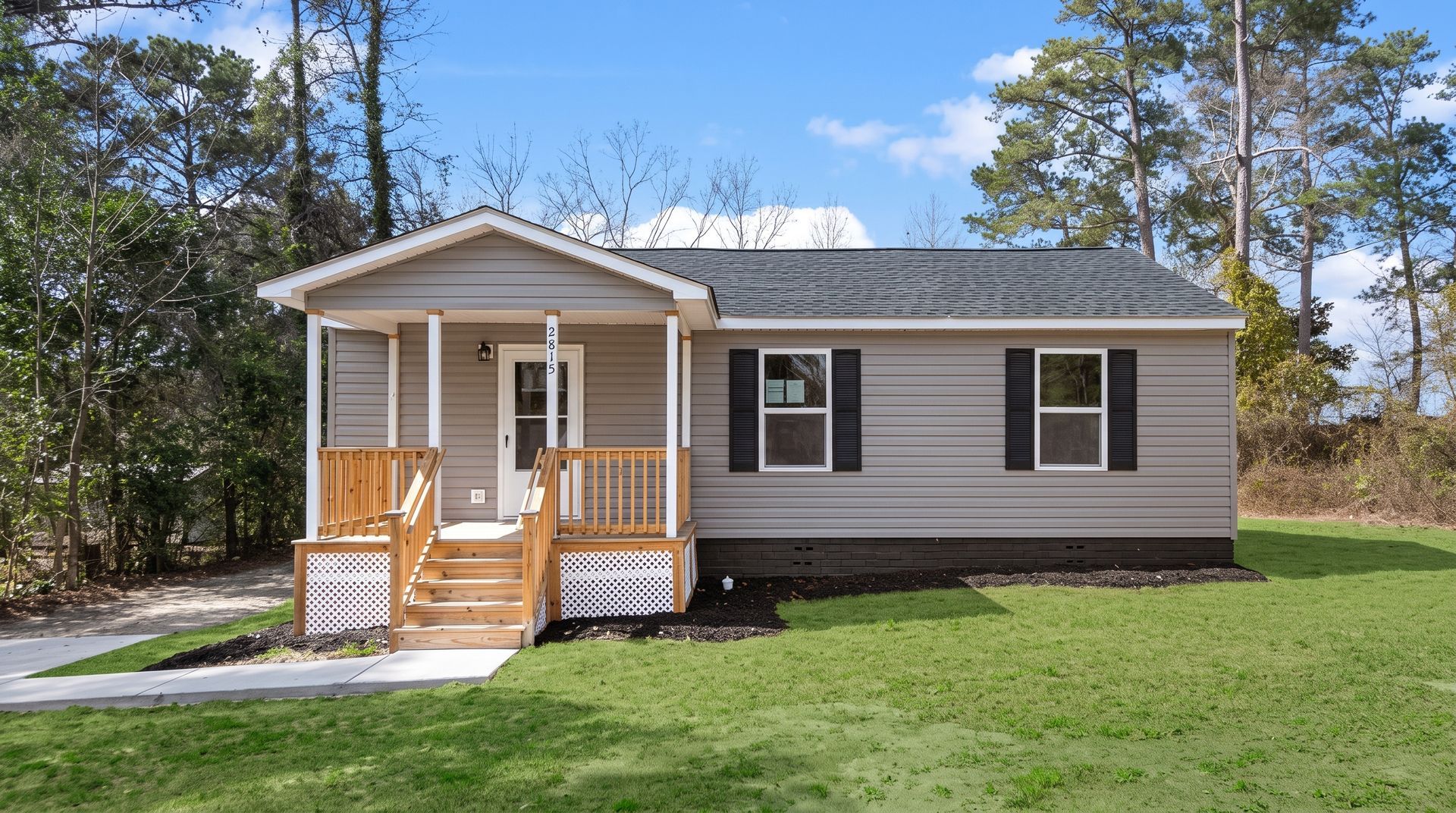 Suburban two-story beige house with a front porch, white garage, and landscaped lawn