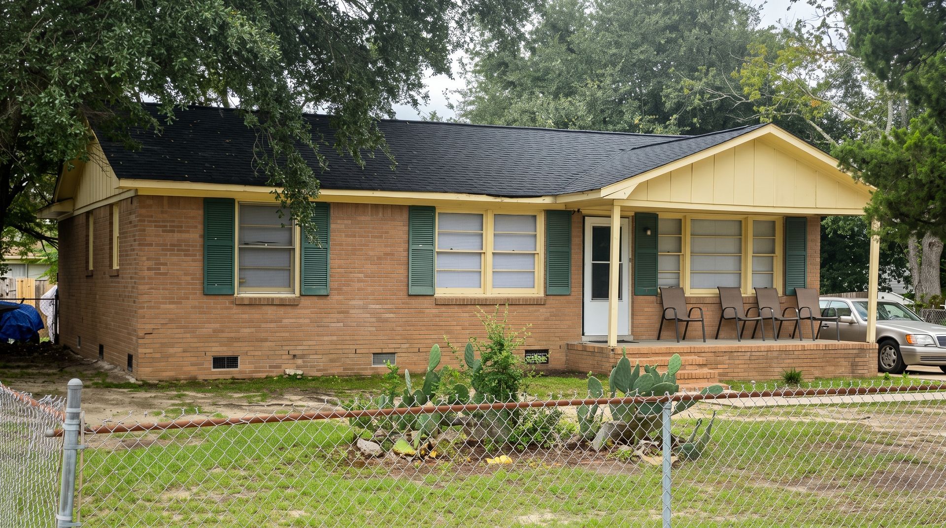 Suburban house with gray roof, beige garage, and manicured lawn on a sunny street
