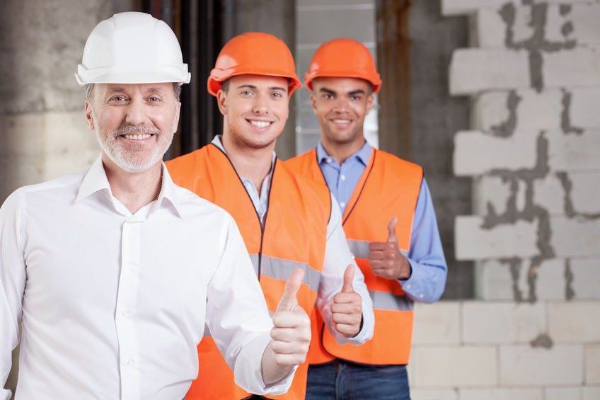 A group of construction workers are giving a thumbs up.