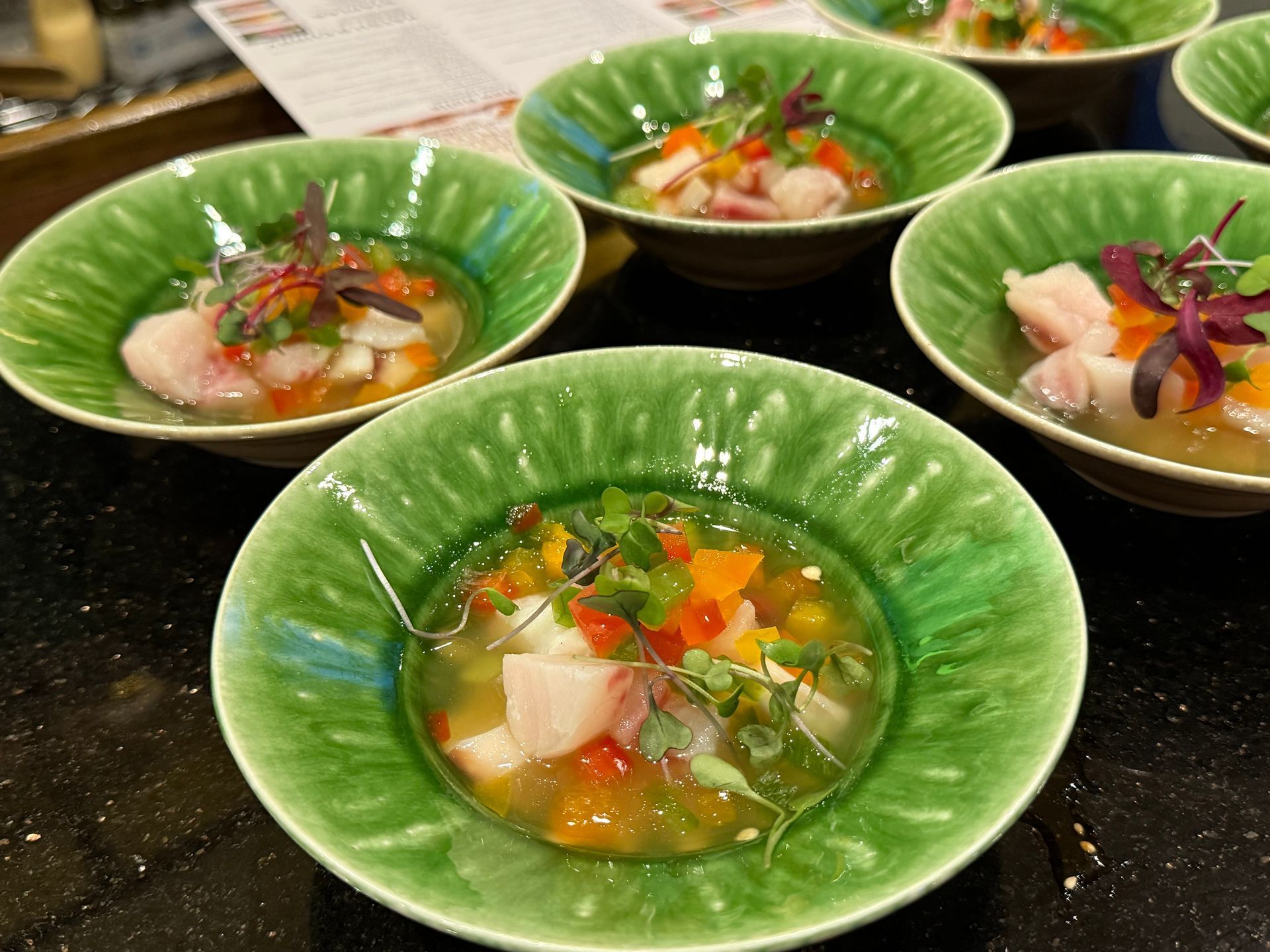 Green bowls of colorful seafood salad on a dark table