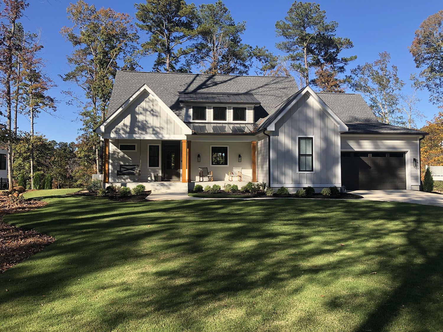 Modern farmhouse with board and batten siding and a metal roof accent built by Raye Construction in Apex NC