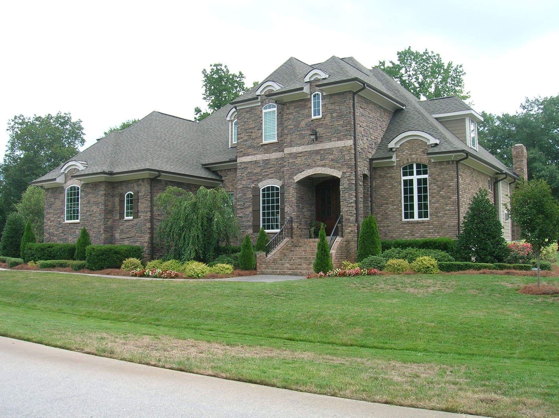 Custom luxury stone and brick estate featuring arched entryway built by Raye Construction in Raleigh NC