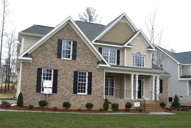 Two-story custom home with stone accent foundation and black shutters built in Apex NC