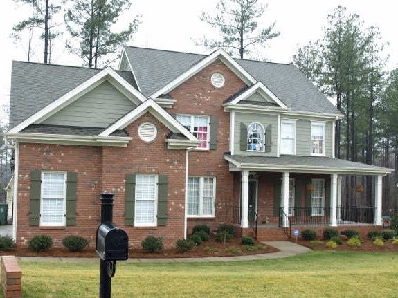 Red brick and green siding custom two-story home with front porch in Wake County NC