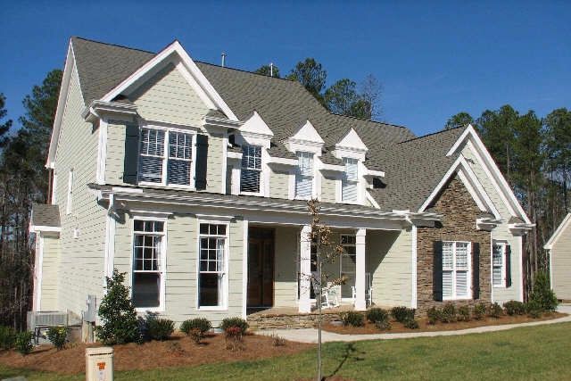 Two-story custom home with light green siding and stone masonry facade built in Apex NC