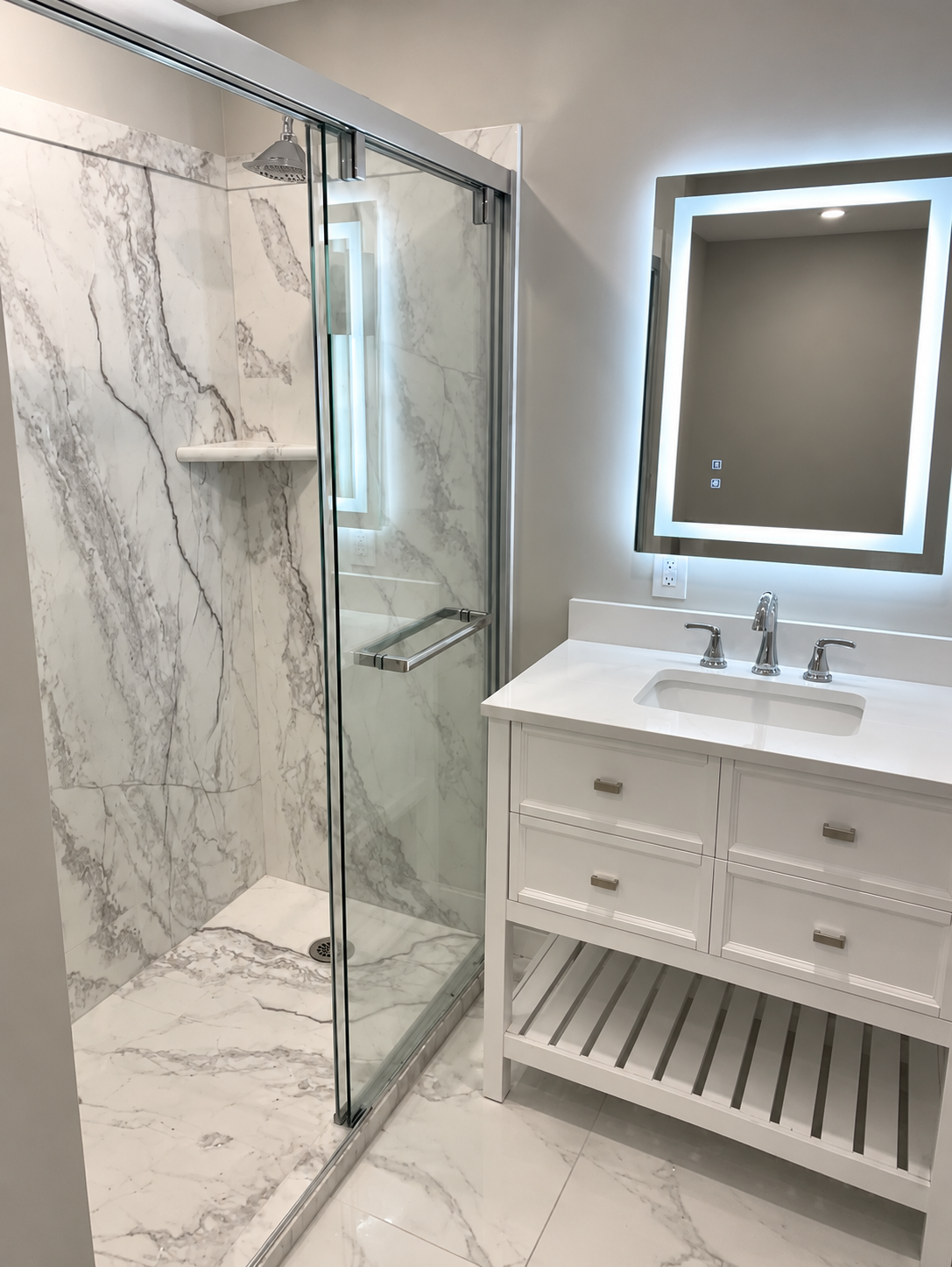Modern bathroom with glass shower, marble walls, white vanity, mirror, and a bucket on the floor