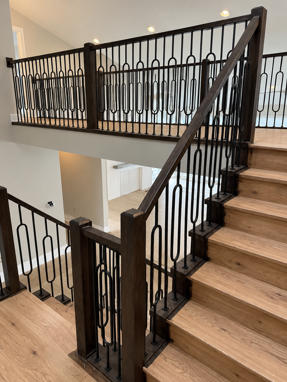 Indoor staircase with beige carpeted steps and black metal railings in a modern home stairwell