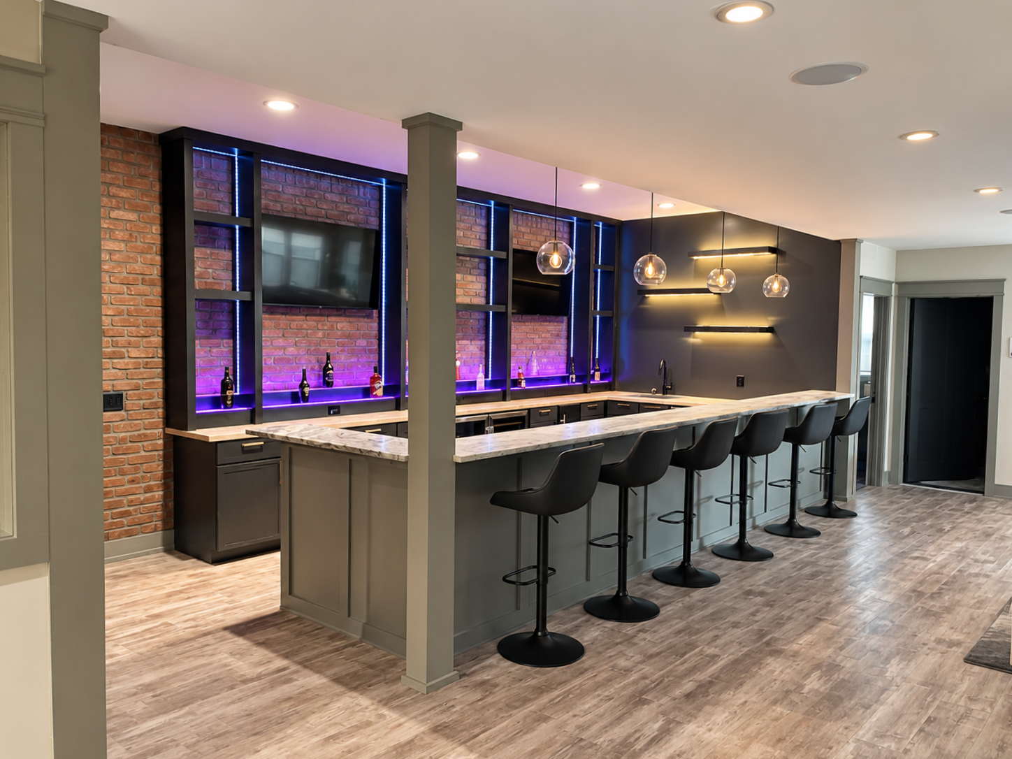 Modern lounge bar with purple lighting, long counter, and high stools in a sleek indoor space