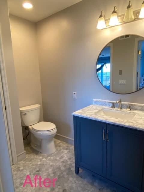 A bathroom with a toilet , sink and mirror.