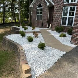 Front walkway with white gravel, brick edging, and a tan path leading to a brick house entrance