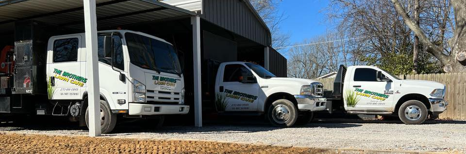 Three white utility trucks parked in a covered industrial bay