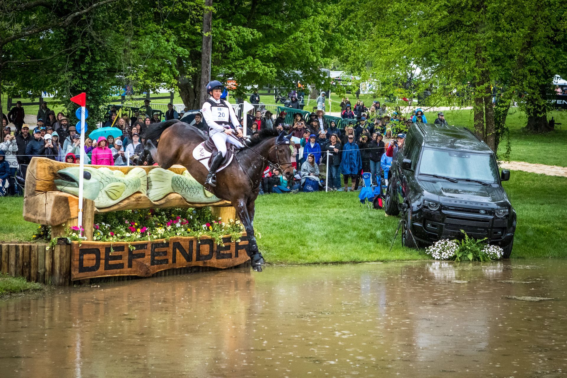 A horse and rider are jumping over a fence in the water.