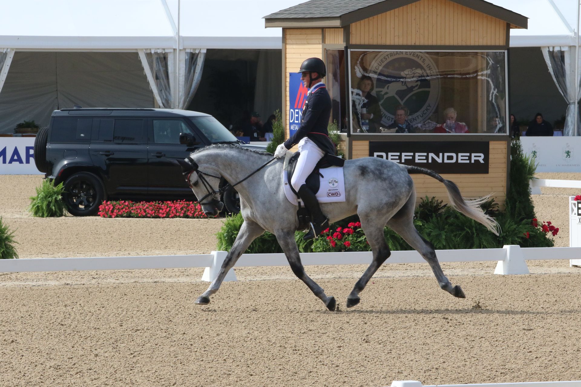 A person is riding a horse in front of a sign that says defender