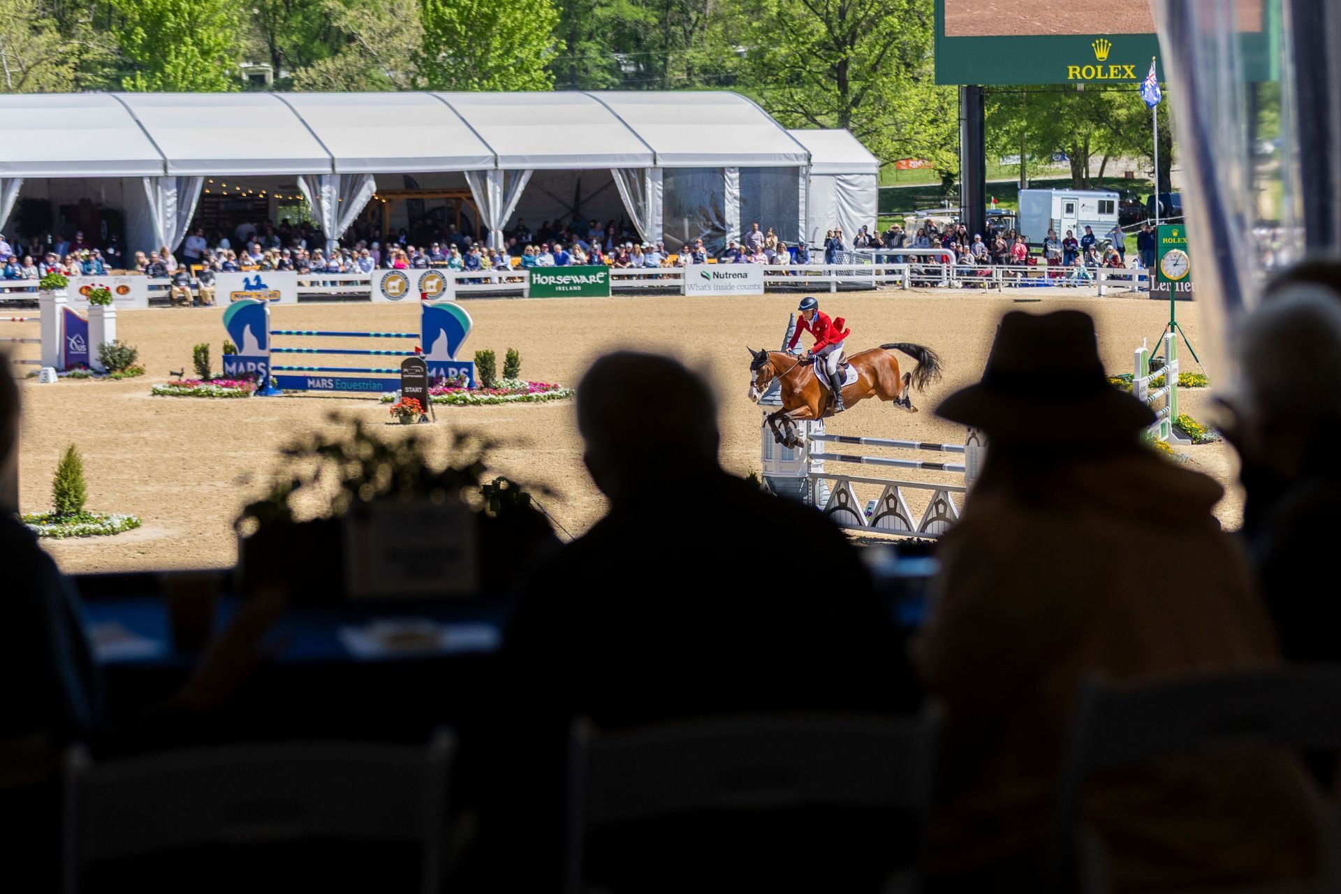 A man on a horse jumping behind a crowd