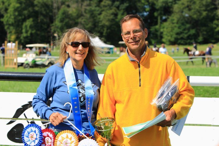 A man and a woman standing next to each other with ribbons around their necks