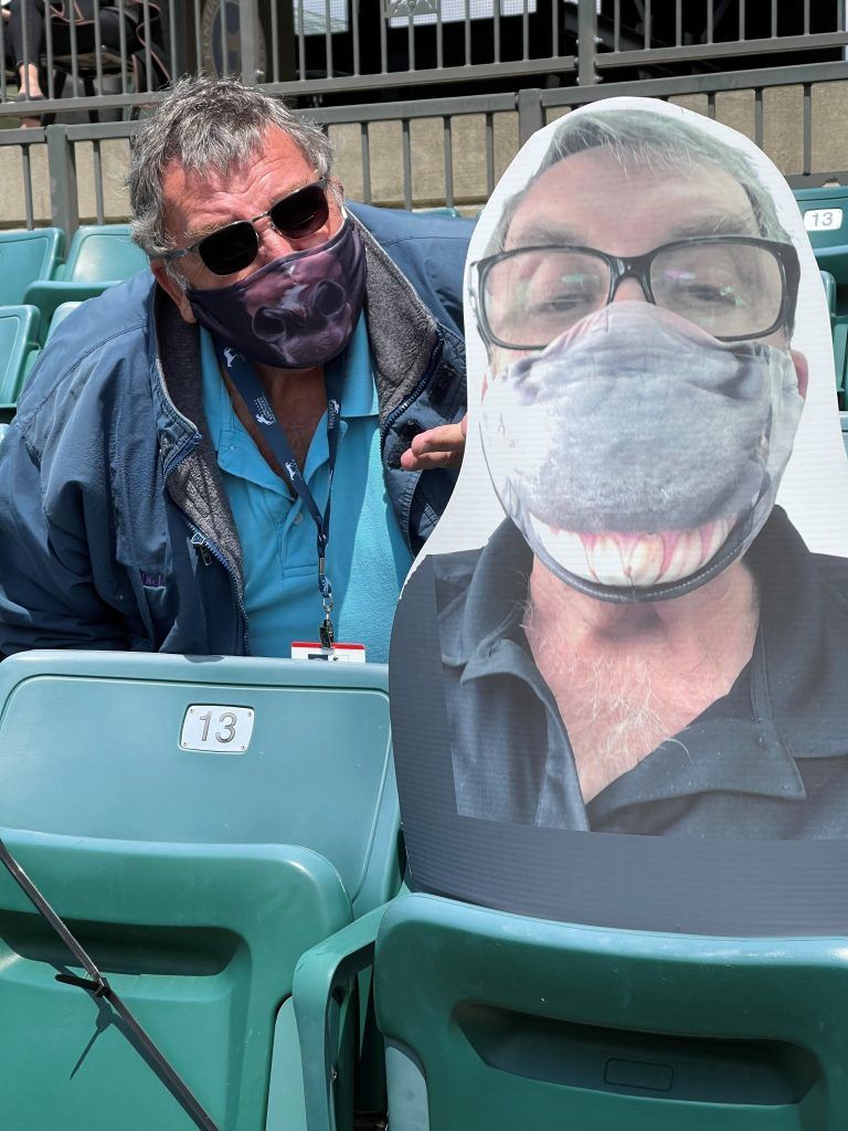 A man wearing a mask and glasses is sitting in a stadium.