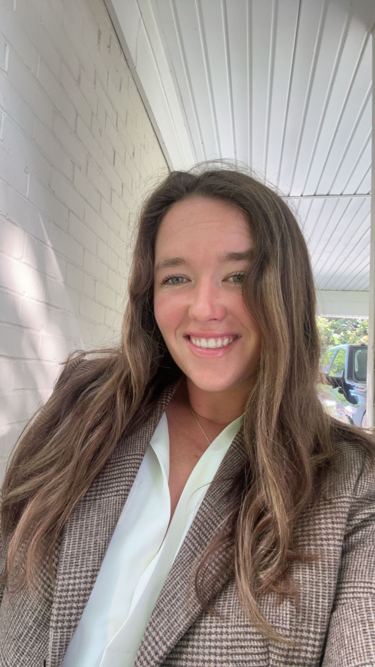 A woman wearing a black jacket and a blue shirt is smiling for the camera.