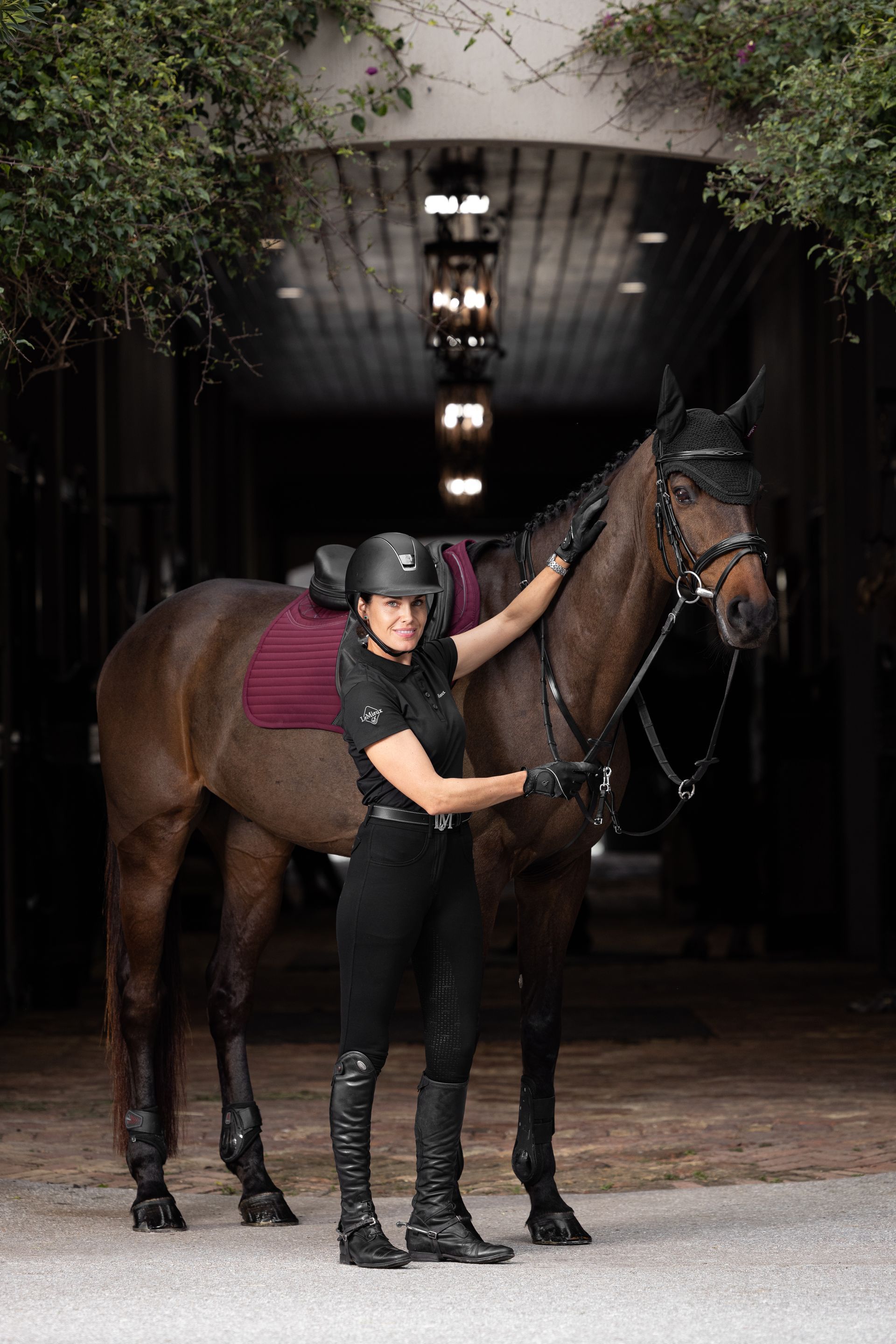A woman is standing next to a brown horse in a stable.