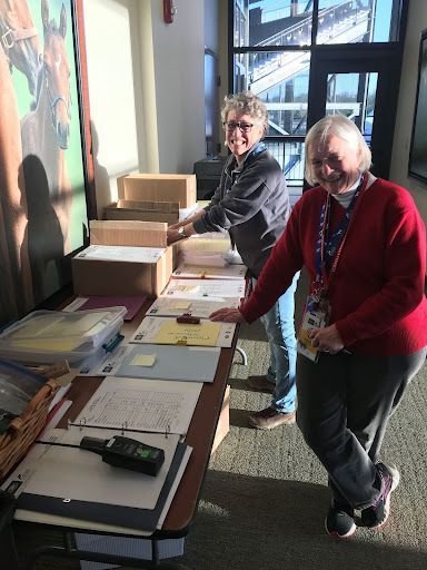 Two women are standing at a table with boxes on it.