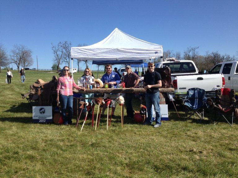 A group of people standing around a table in a field.