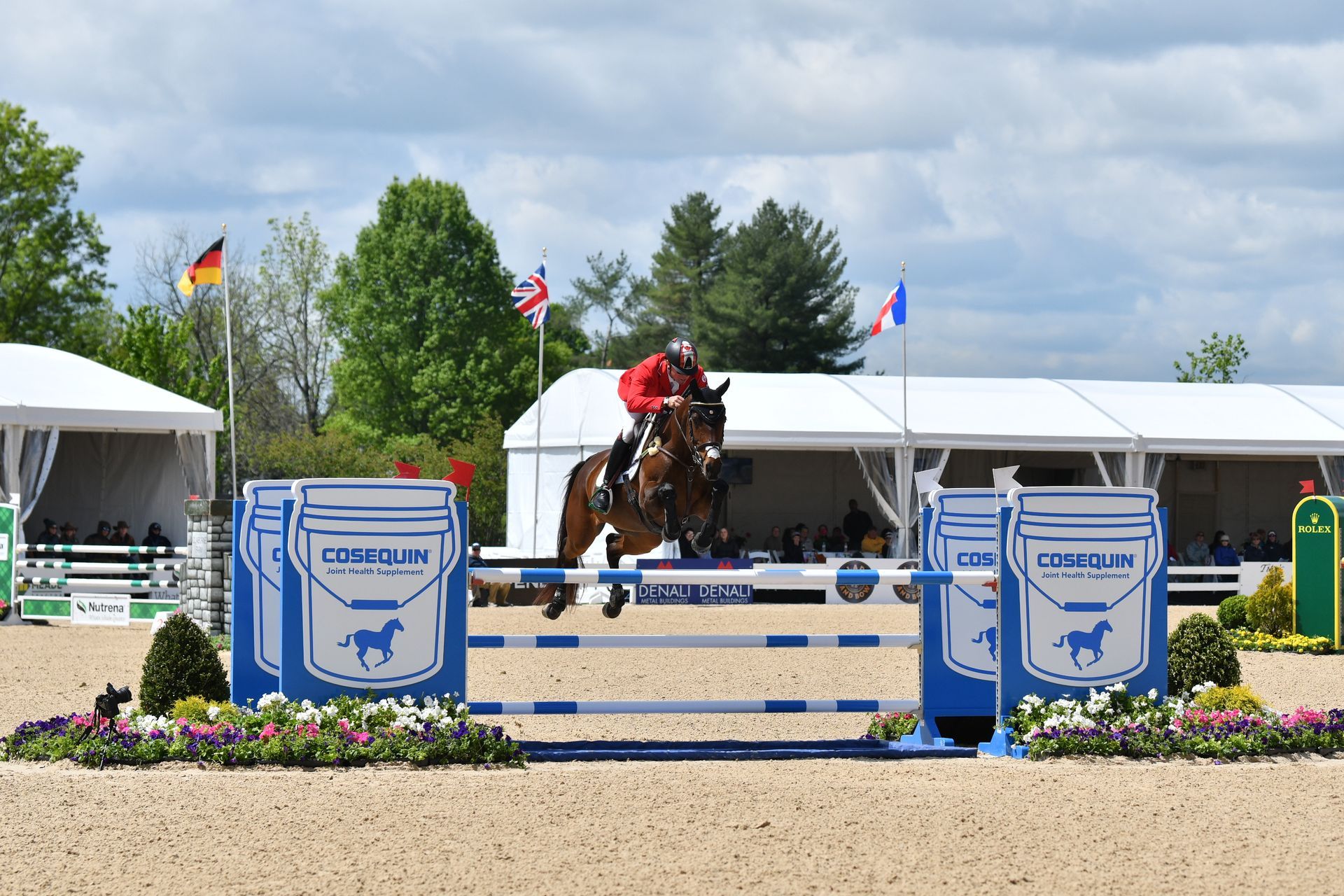 A person riding a horse jumping over a fence with a bucket on it
