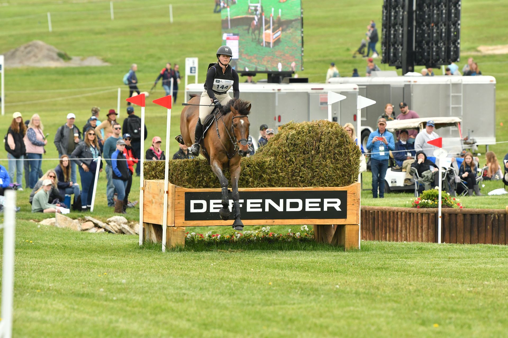 A person is riding a horse over a wooden fence.