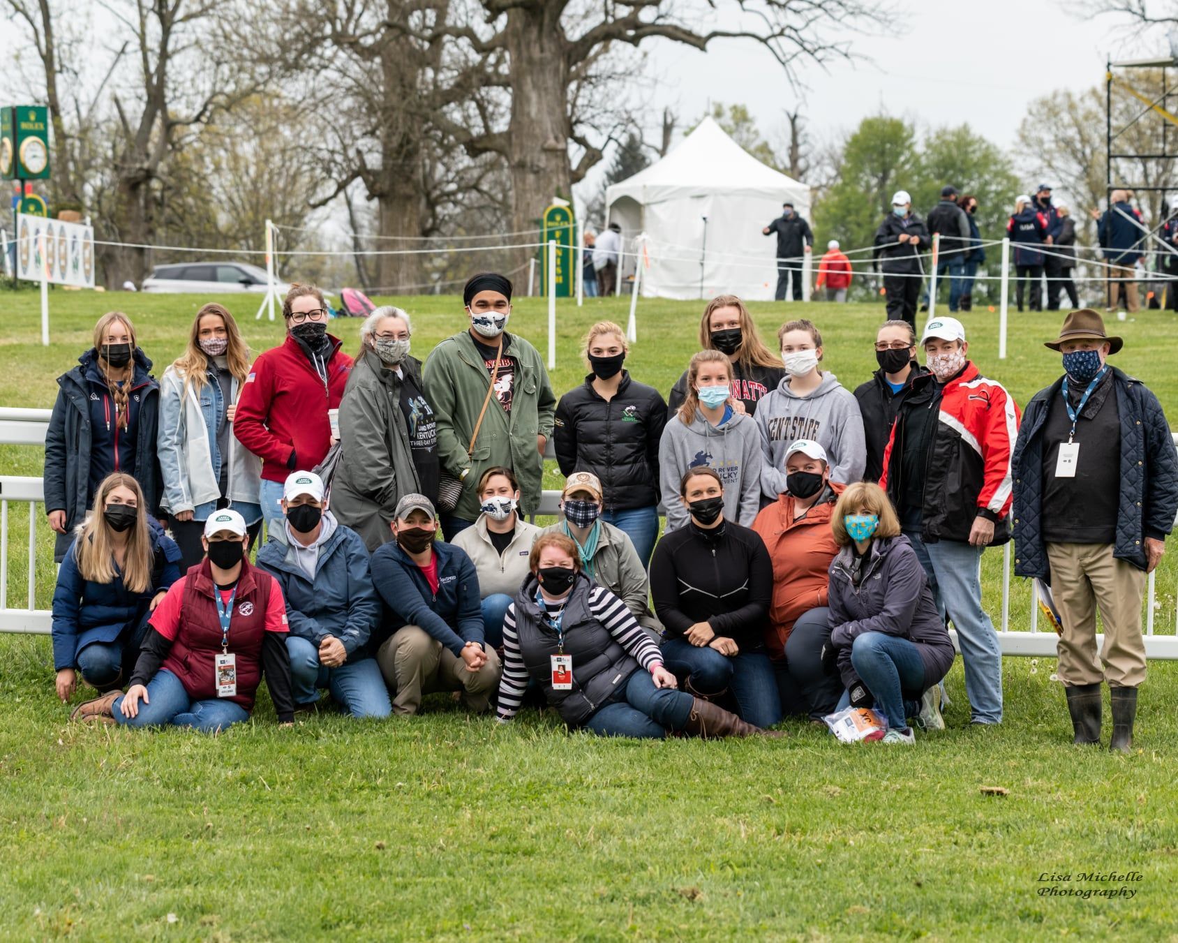 A group of people wearing masks are posing for a picture in a field.