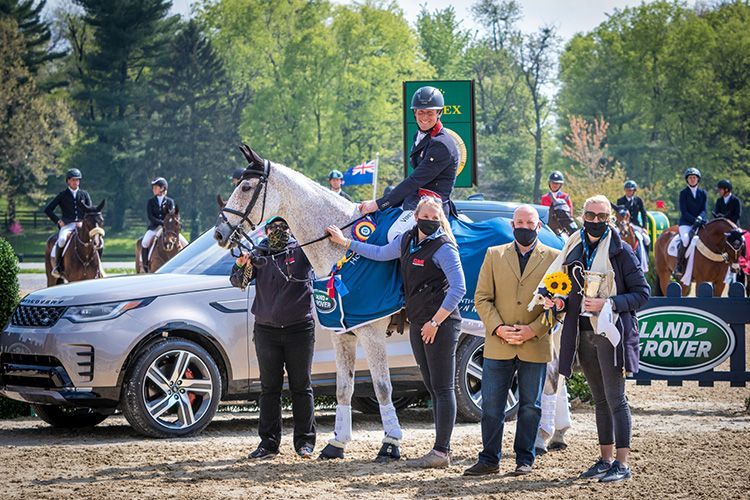 A man is riding a horse in front of a land rover.