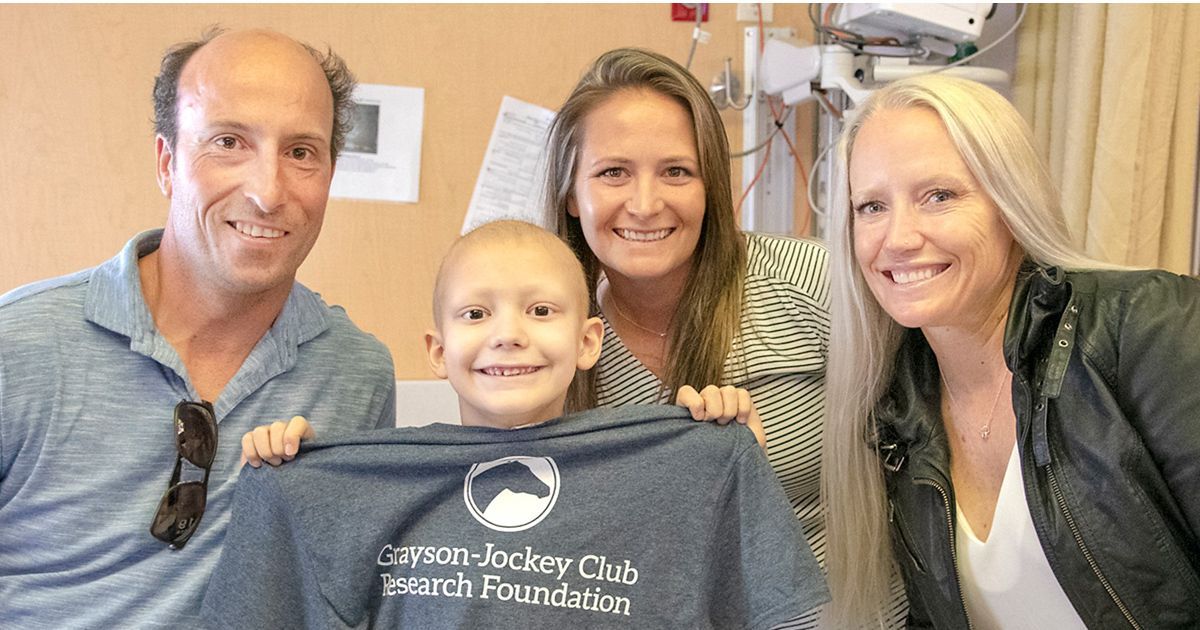 A group of people are standing around a young boy holding a t-shirt.