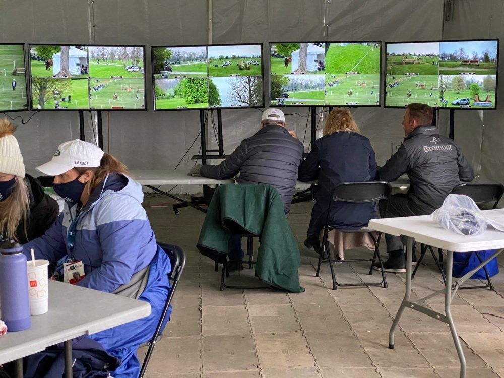 A group of people are sitting at tables in front of televisions.