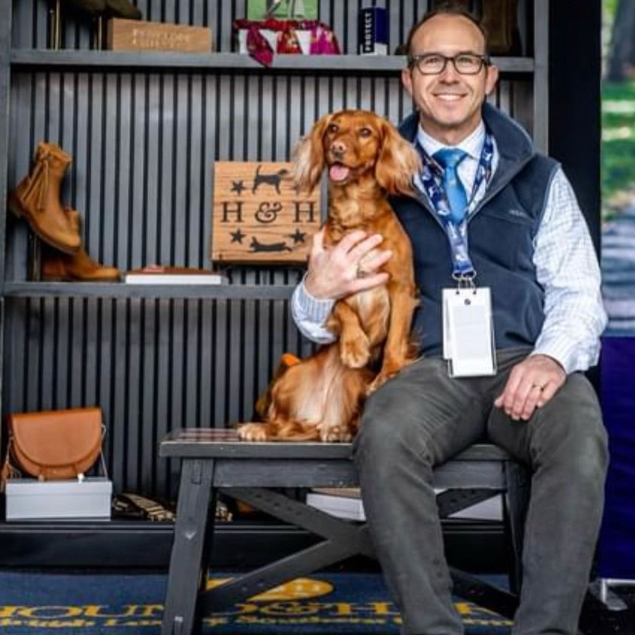 A man is sitting on a bench holding a brown dog