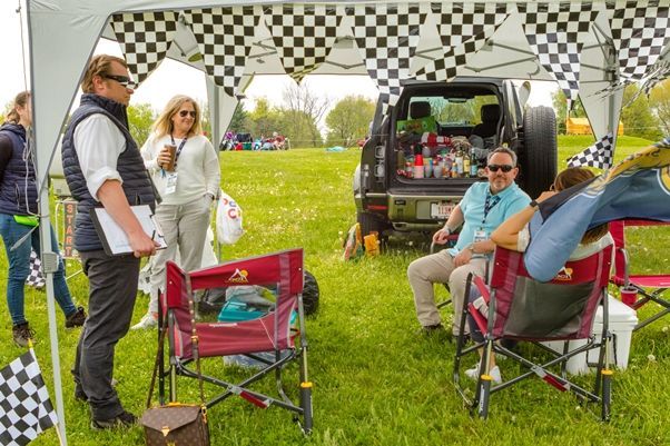 A group of people are sitting under a tent in a field.