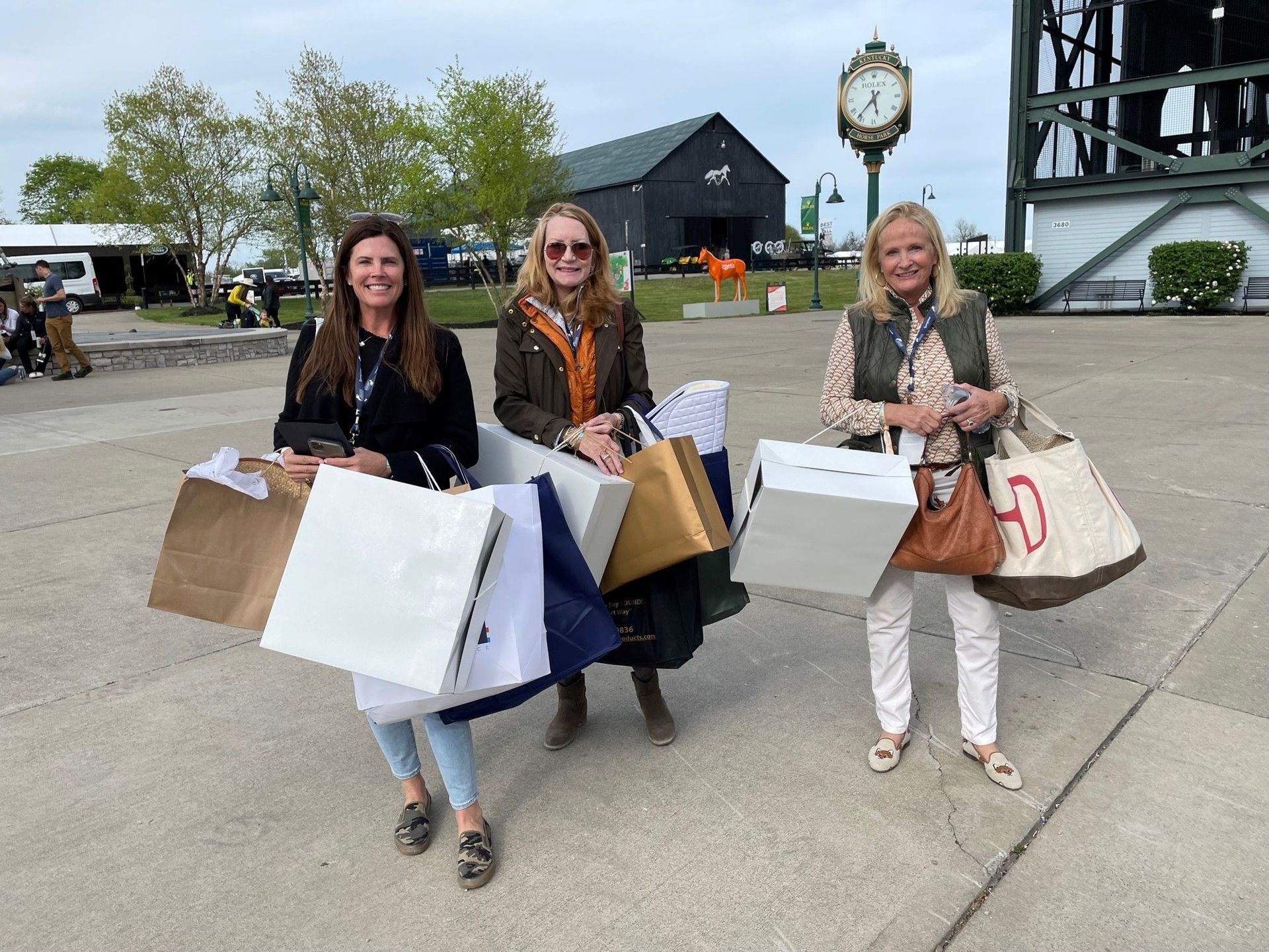 Three women are standing next to each other holding shopping bags.