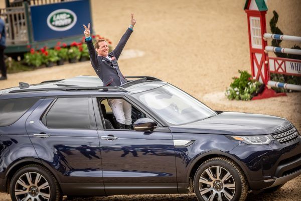 A woman is sitting in a car with her arms in the air.