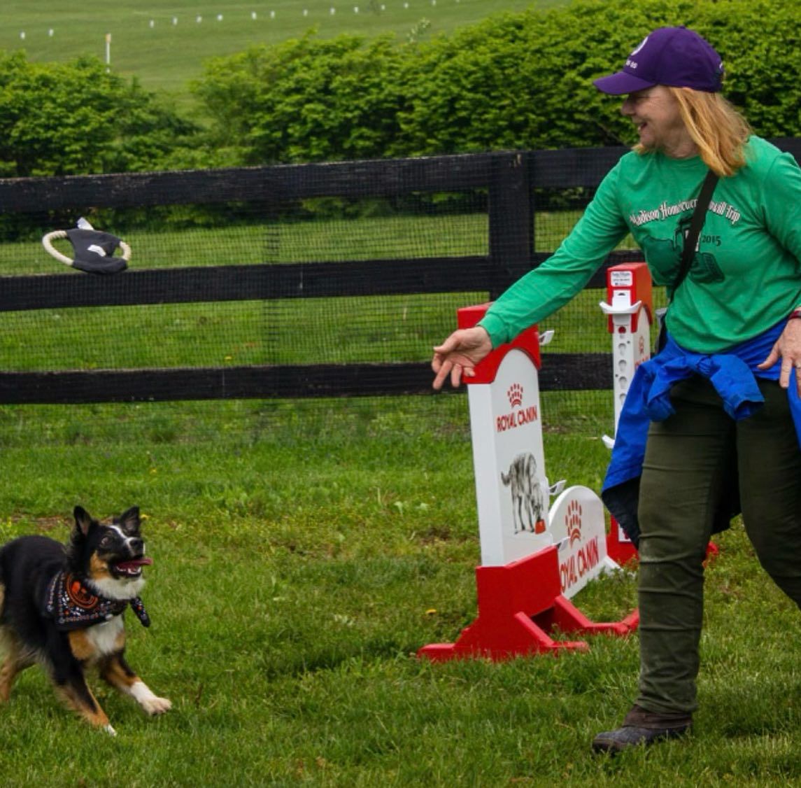 A woman in a green shirt is standing next to a dog