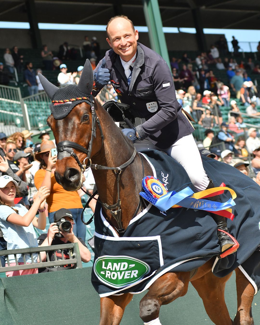 A man is riding a horse with a blanket that says land rover on it