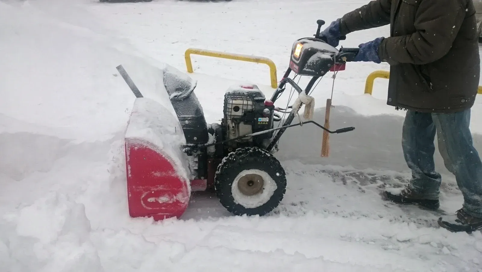 A man is using a snow blower to remove snow from the ground.