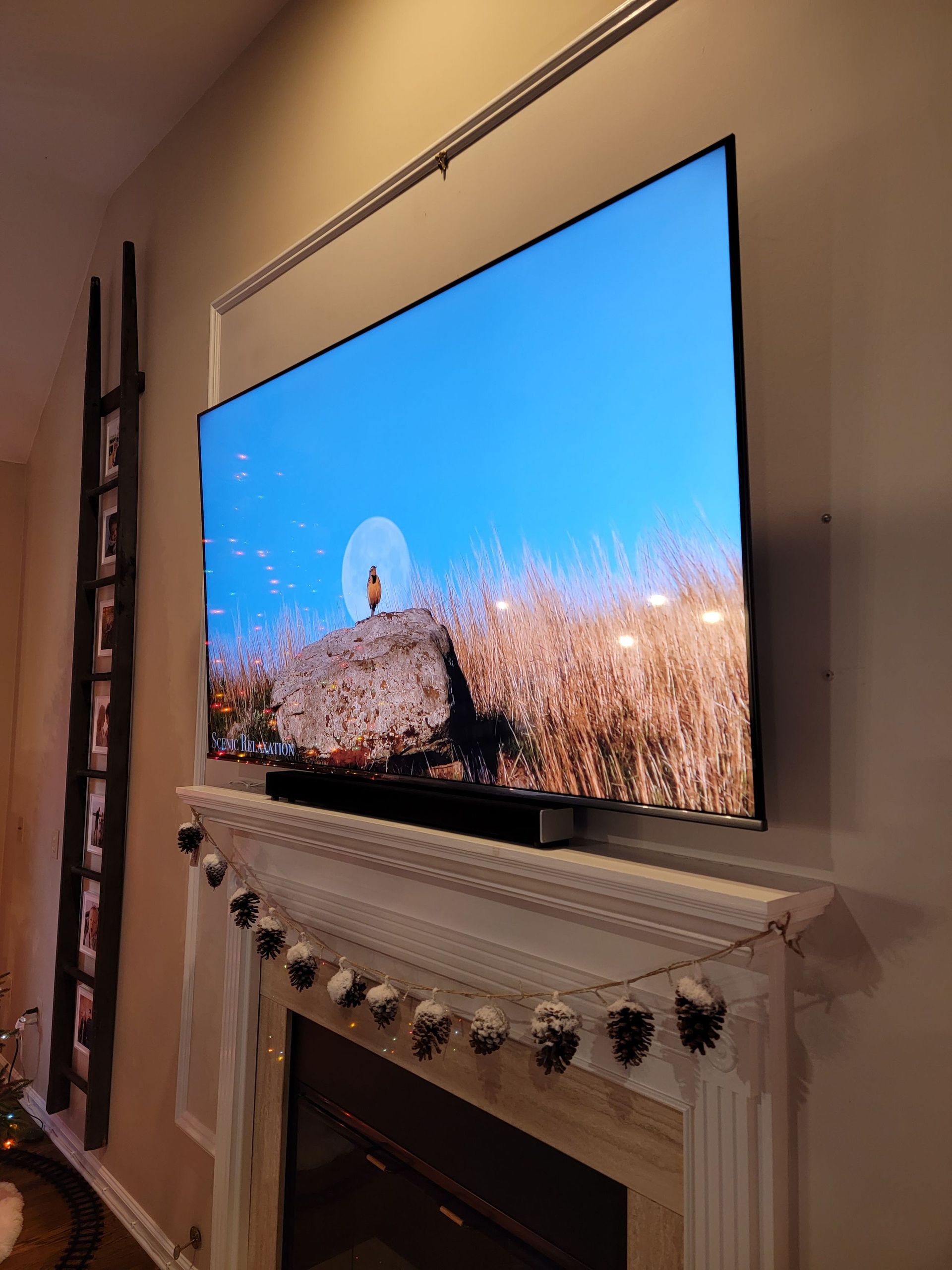 TV mounted above fireplace in a cozy room, showing a bright landscape scene by Audio Video Concepts