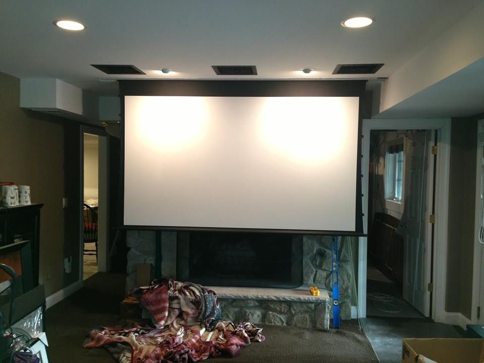 Home theater room with a large projection screen and ceiling lights, with a pile of fabric by Audio Video Concepts