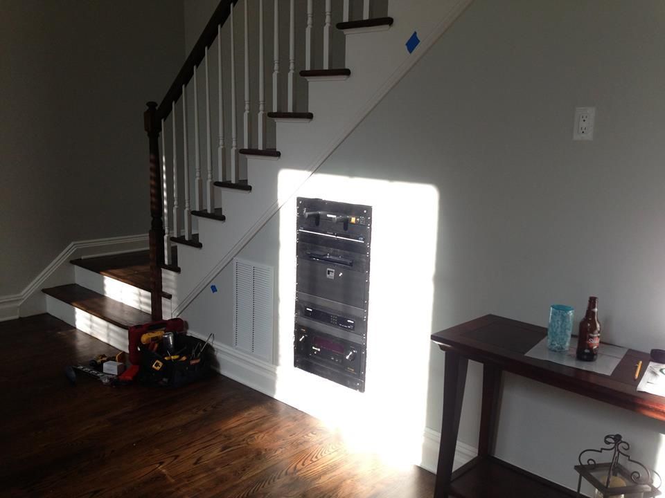 Staircase and hardwood room with wall cabinet, small table, and bright sunlit patch on the wall by Audio Video Concepts