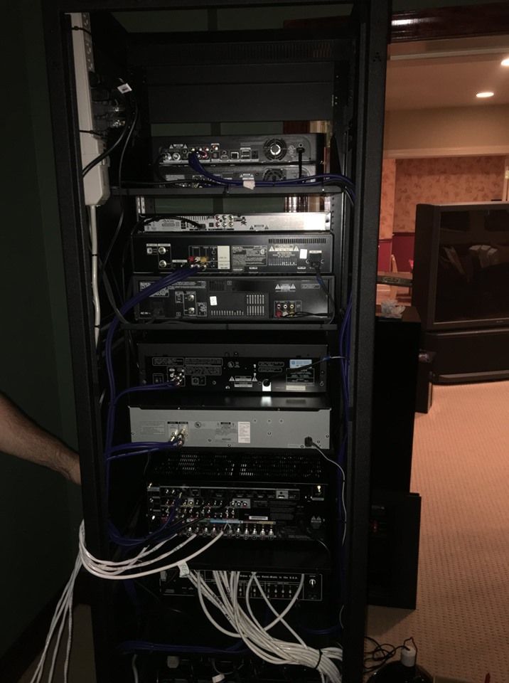 Open server rack with stacked audio and network equipment, cables running out the bottom by Audio Video Concepts