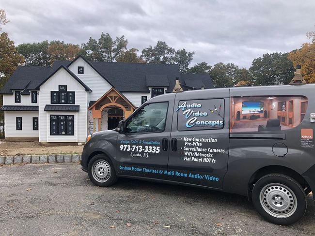 Branded black service van parked in front of a white building on a cloudy day by Audio Video Concepts
