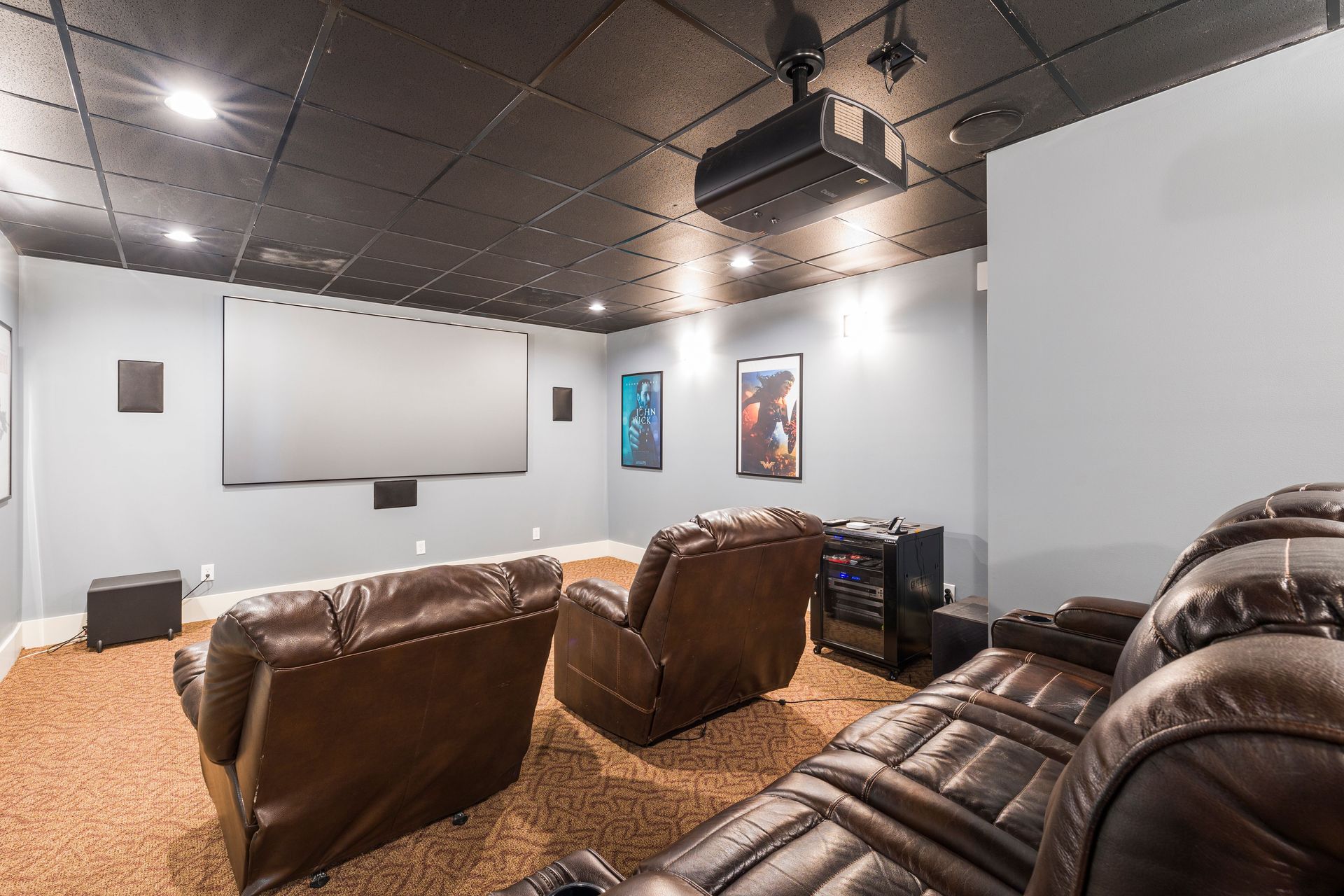 Home theater room with leather recliners, large screen, wall art, and ceiling projector by Audio Video Concept