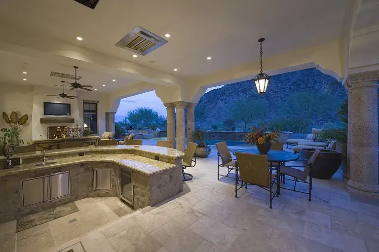 Luxury outdoor patio with kitchen, seating, and ocean view at dusk by Audio Video Concept
