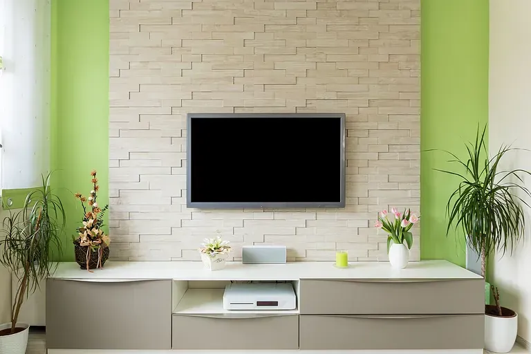 Modern living room with wall-mounted TV, white console, and green accent walls by Audio Video Concept